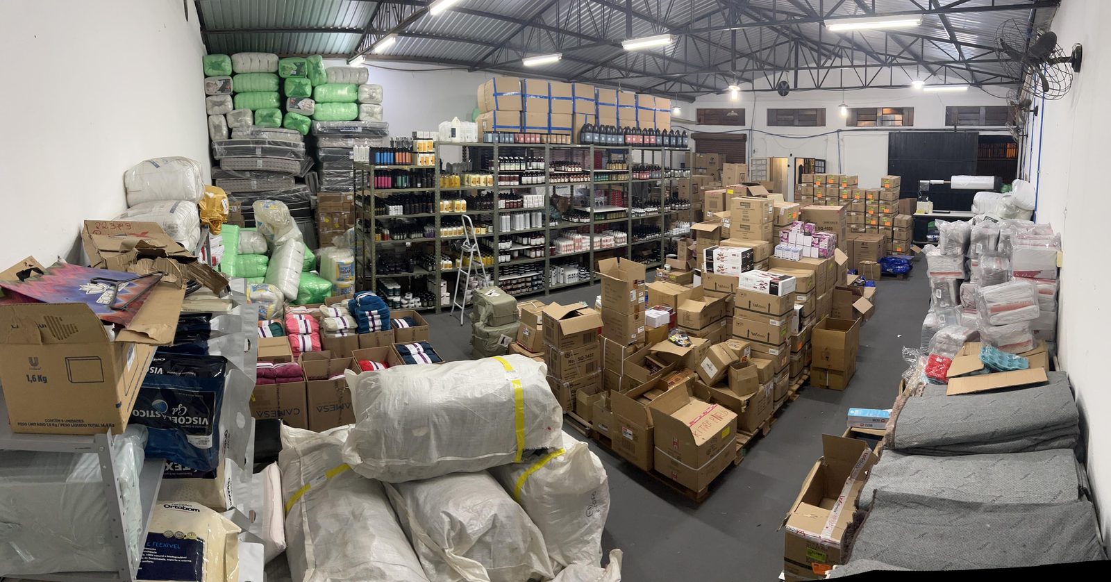 Primeiro estoque da Domus, com caixas, colchões e prateleiras de produtos