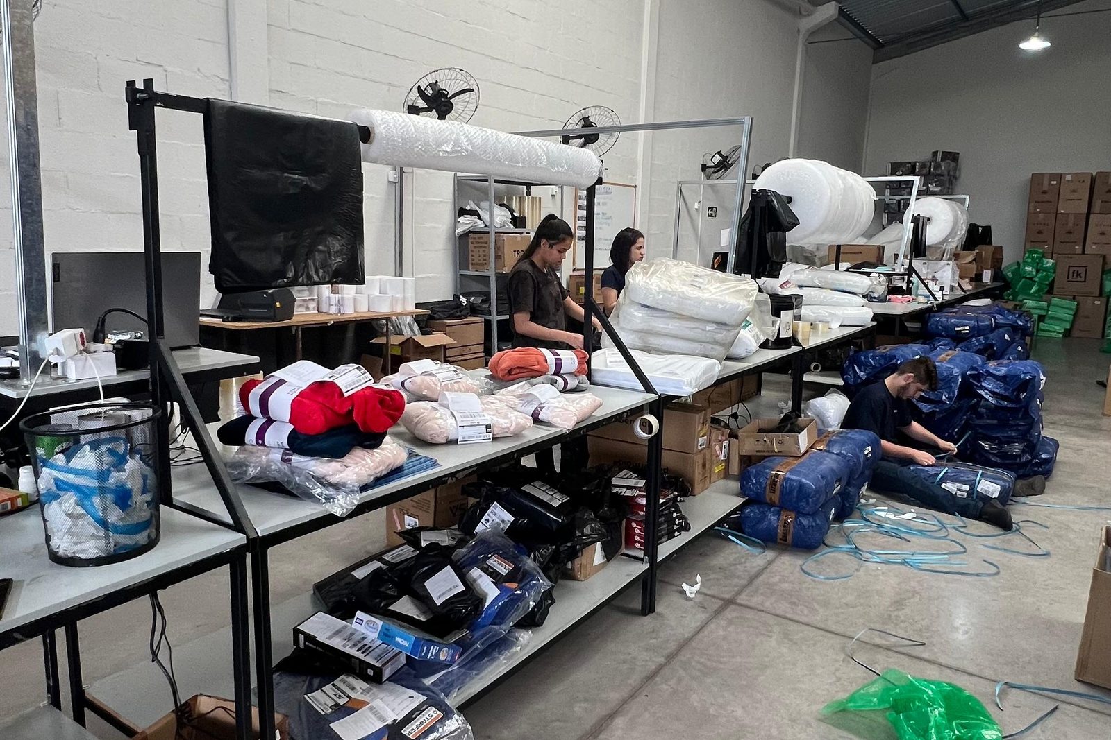 Equipe embalando pedidos nas bancadas da expedição