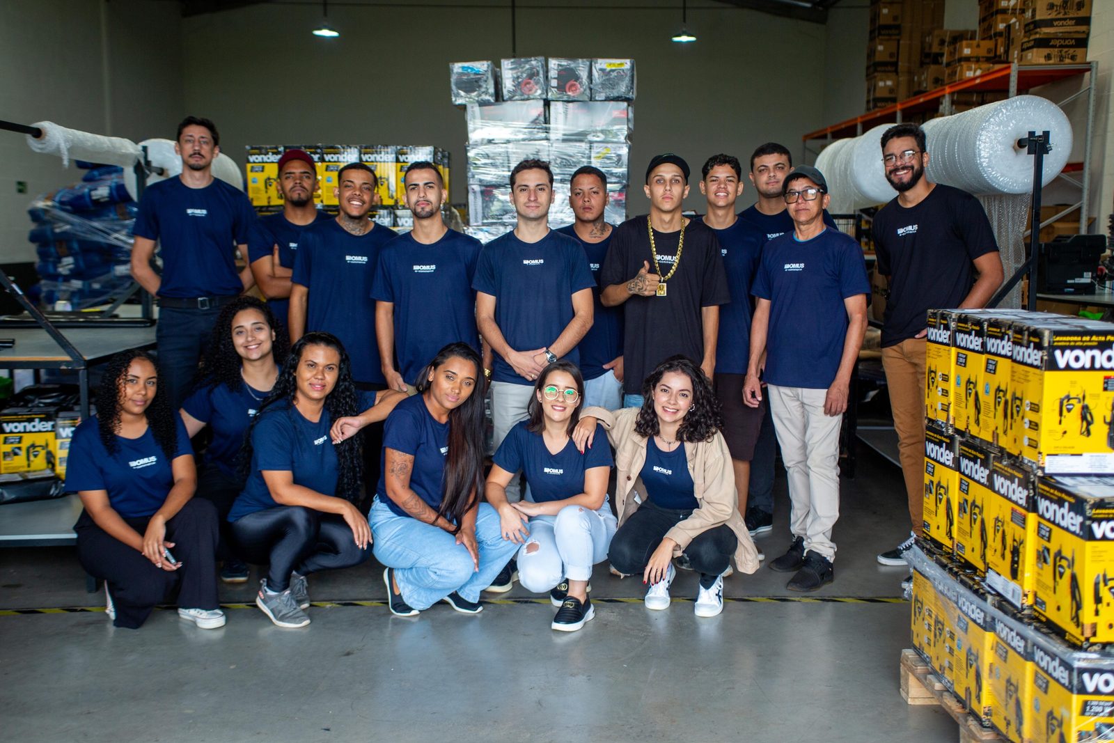 Equipe da Domus reunida no galpão, ao lado de caixas da Vonder